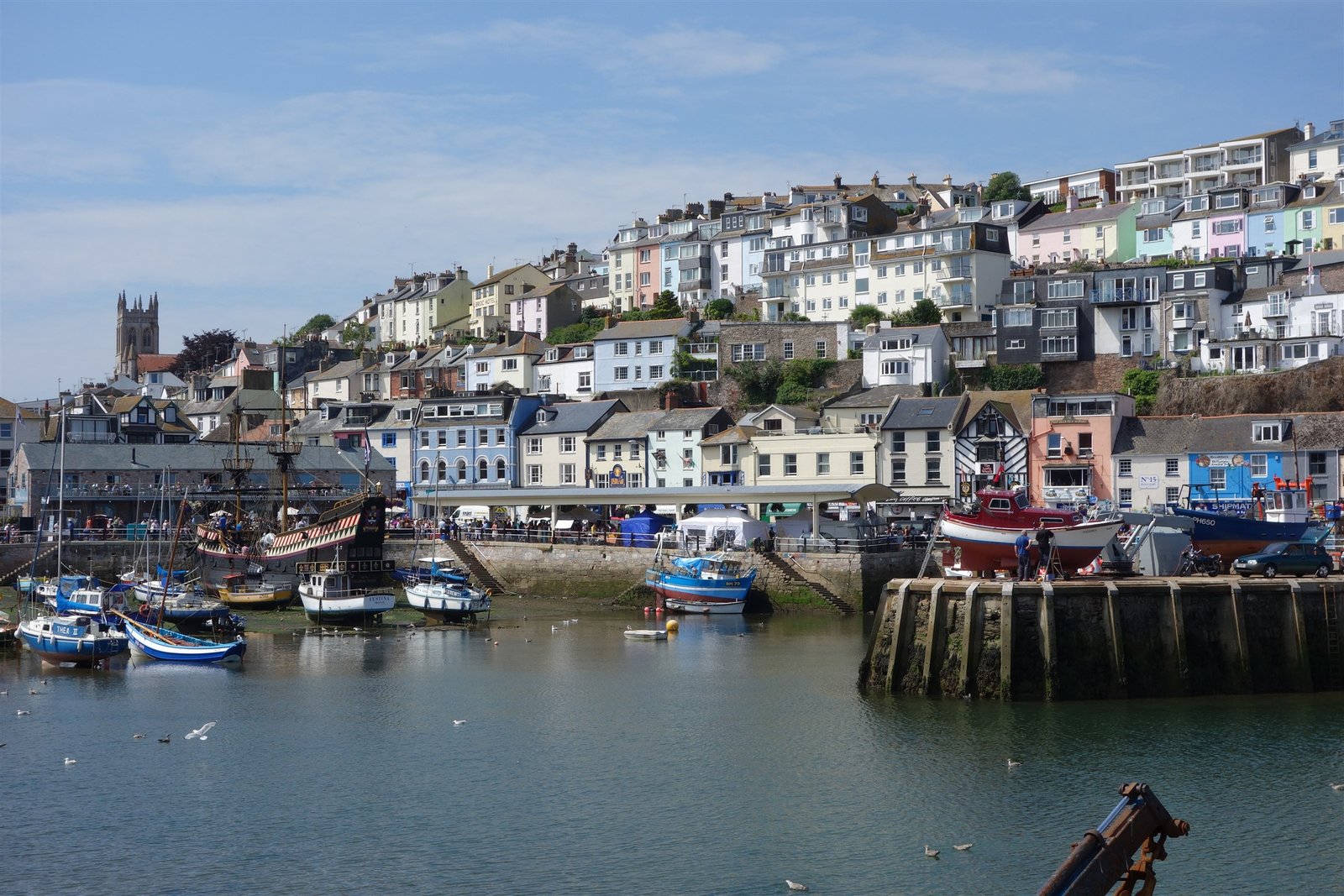 Boats in Brixham harbour beneath colourful hillside homes